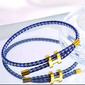 Braided in two shades of blue with gold-tone metal details and an elegant “H”